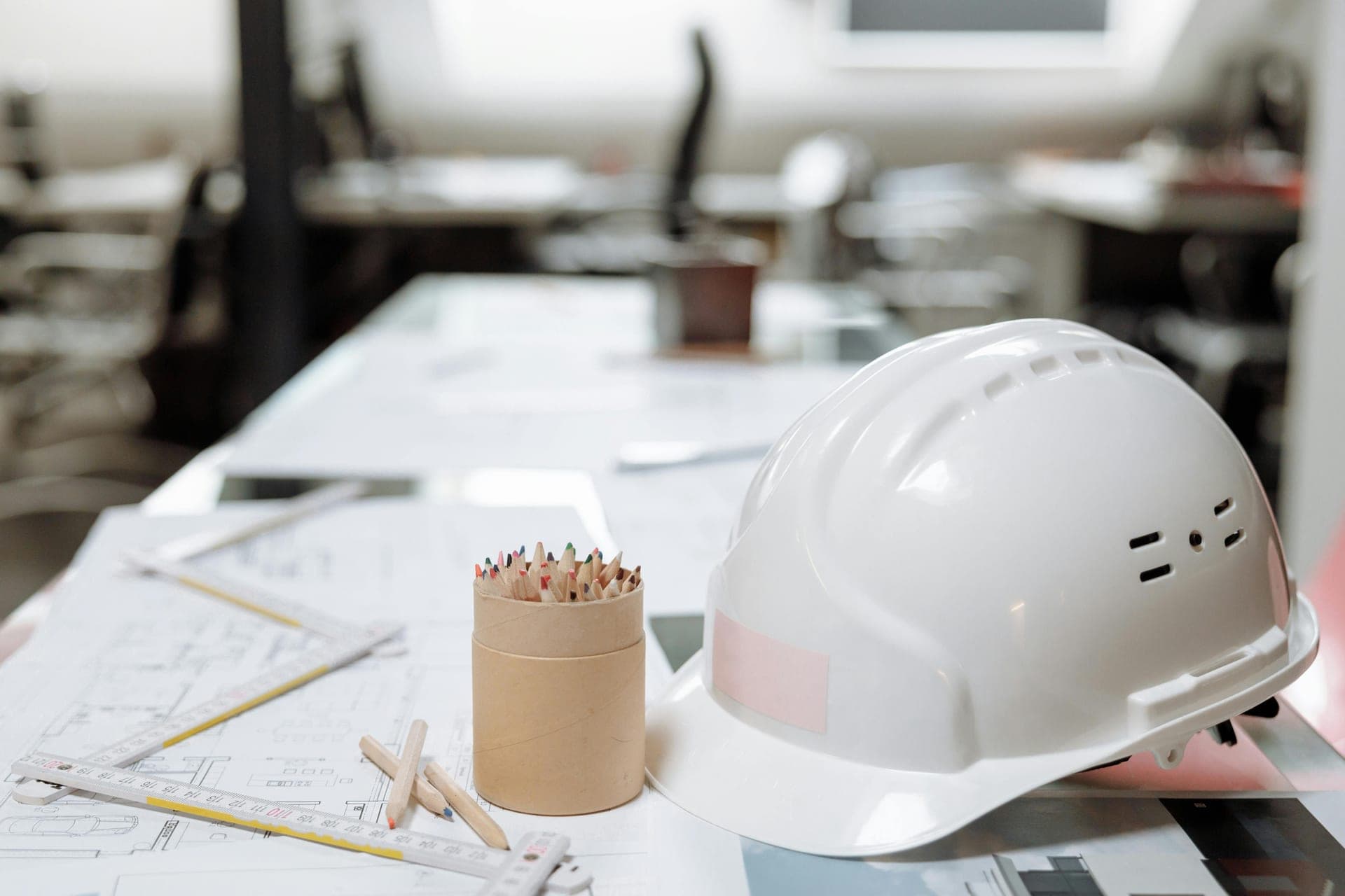Ingeniero con casco blanco analizando planos técnicos en una obra